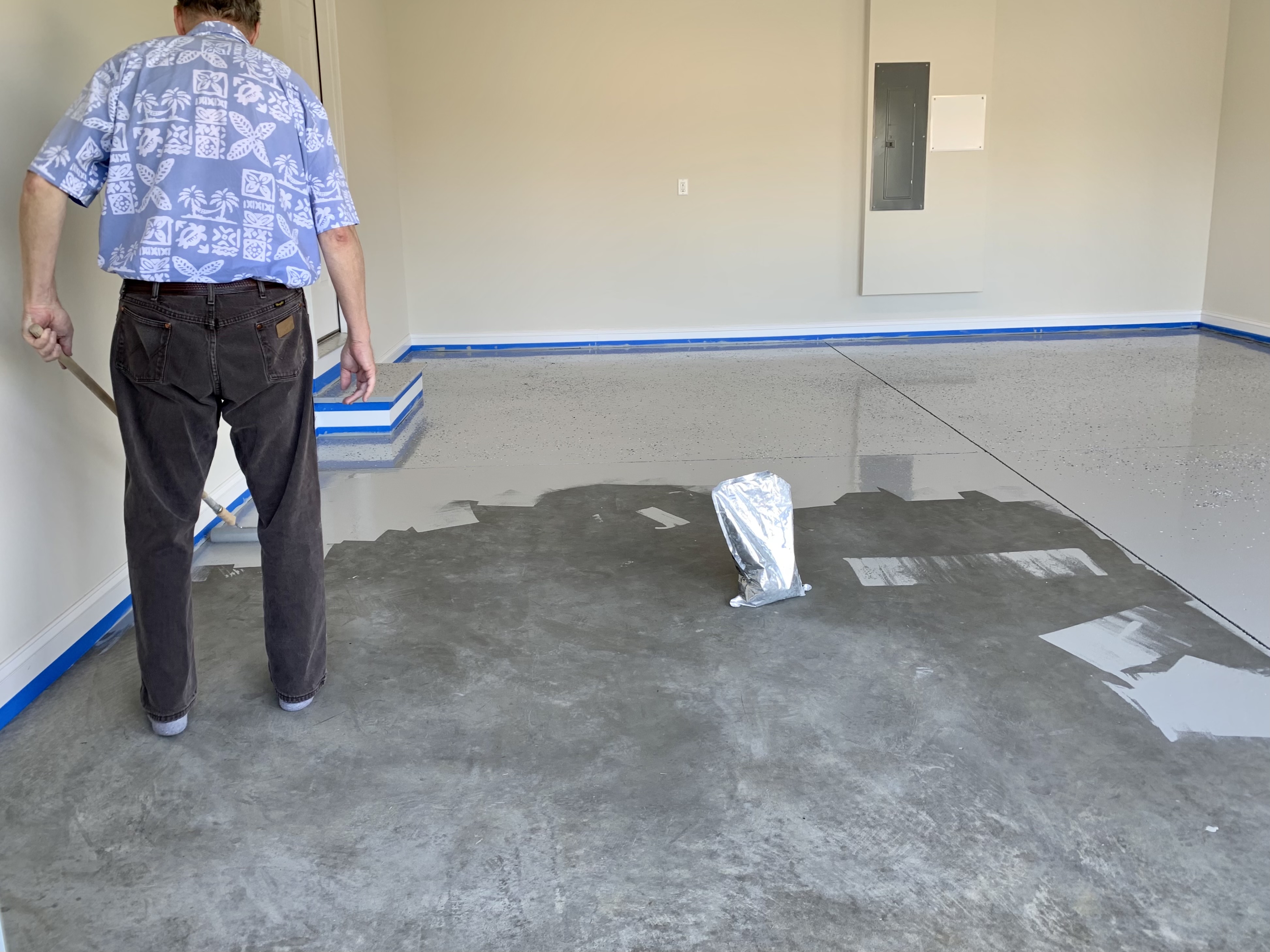 Homeowner applying polyurea coating to a garage floor — the application process requires working quickly before the product sets